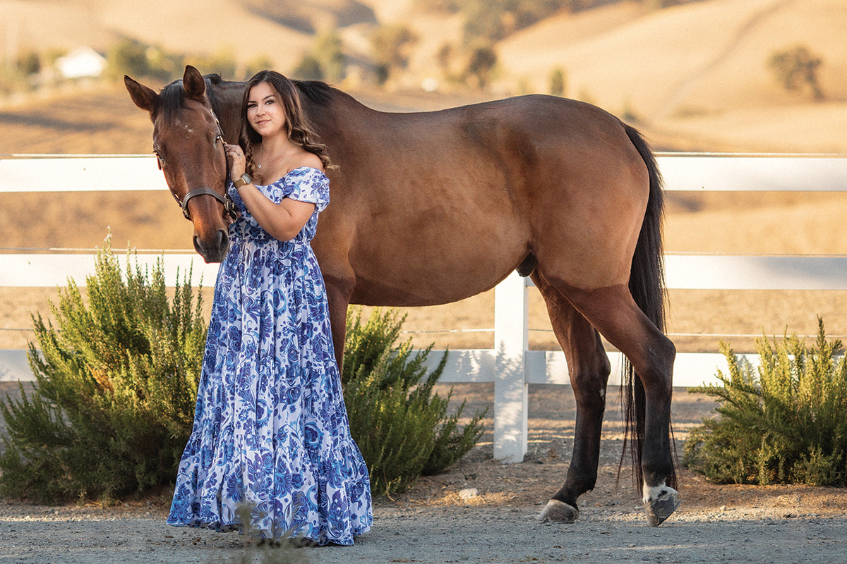 An equestrian of color in a dress with her horse